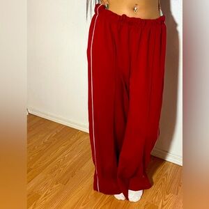 Red polyester wide leg pants, with thin white stripes on the sides.
